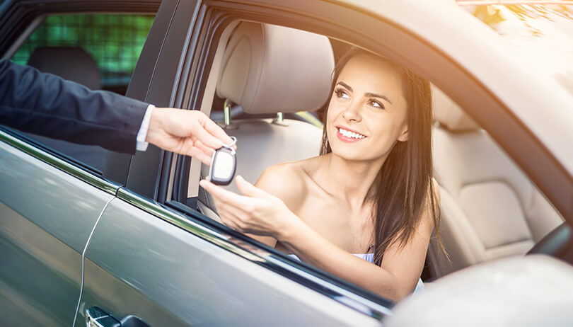 Woman buying a new car and receiving the keys